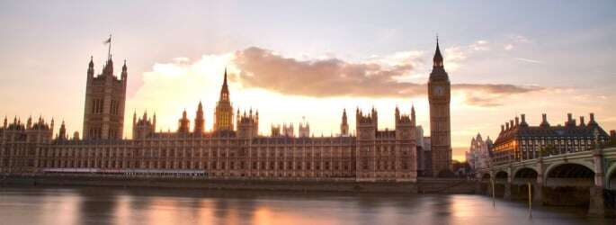 Image shows the sun rising behind the Houses of Parliament.