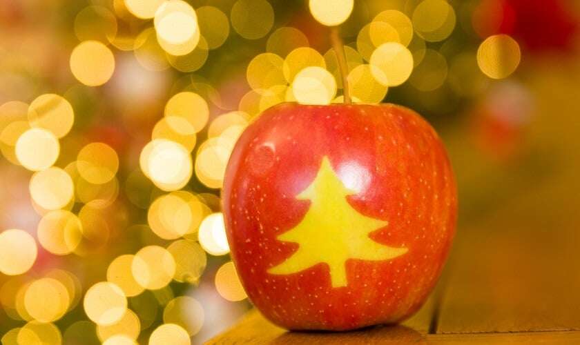 Image shows an apple decorated with a Christmas tree stamp.