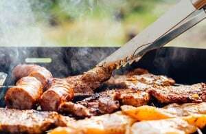 Image shows someone barbecuing sausages and other meat.