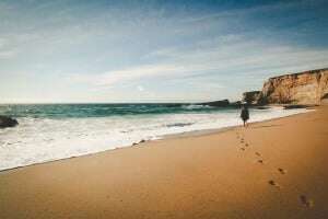 Image shows someone walking on a beach.