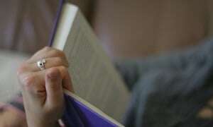Image shows someone reading a book with a purple cover.