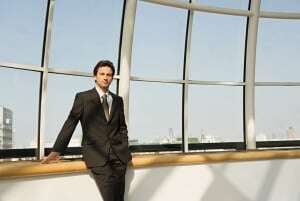 Image of a businessman in a suit standing by a large window.
