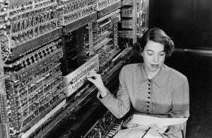 Image shows a programmer at a 1950s computer.