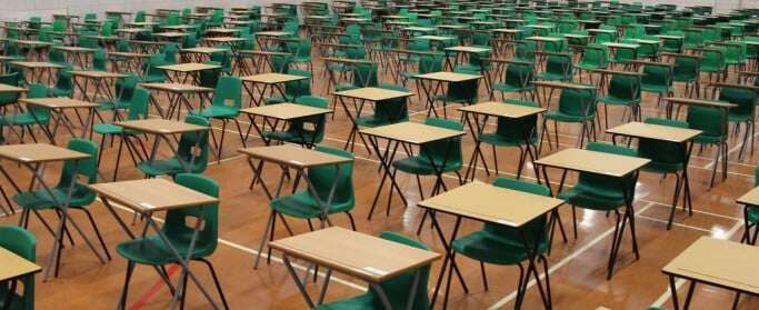 Image shows rows of green exam desks.