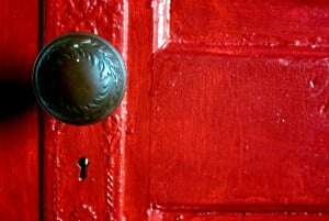 Image shows a doorknob on a red door.
