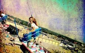 Image shows a woman looking very enthusiastic on a carousel.