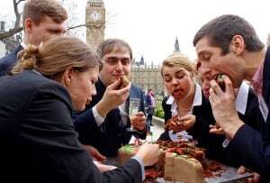 Image shows protesters dressed as politicians gorging themselves on a cake in the shape of Africa.