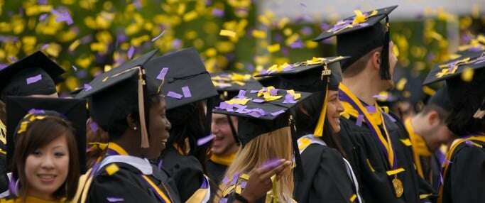 Image shows graduating students being showered in yellow and purple confetti.