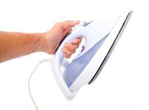 Image shows a hand holding out an iron.