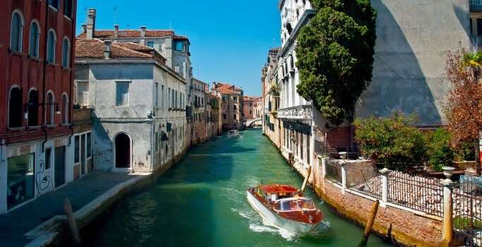 Image shows a boat on a canal in Venice.