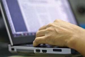 Image shows someone working on a laptop.