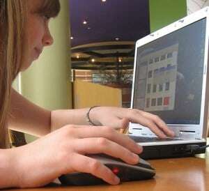 Image shows a young woman on a laptop.