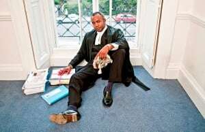 Image shows a barrister holding his wig in his hand.