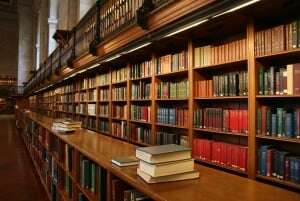 Image shows a long wooden bookshelf in an old library.