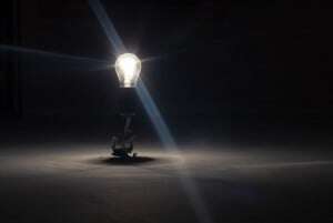 Image shows a lightbulb in a dark room. 
