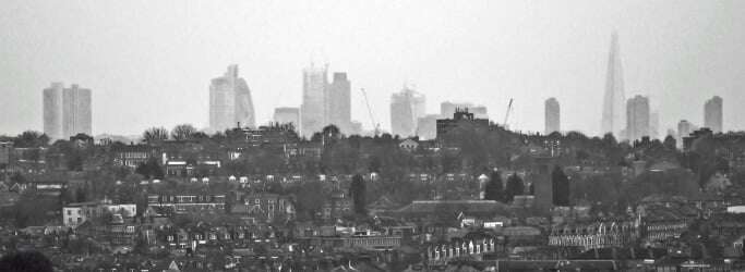Image shows London, with terraced houses in the foreground and skyscrapers in the background.