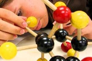 Image shows a girl looking at a model of a molecule.