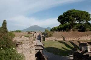Image shows the ruins of Pompeii, with Vesuvius in the background. 