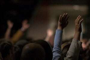 Image shows hands being raised to ask questions.