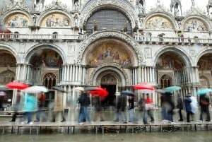 Image shows a queue in the rain in Venice.