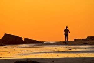Image shows someone running on a beach in golden sunlight.