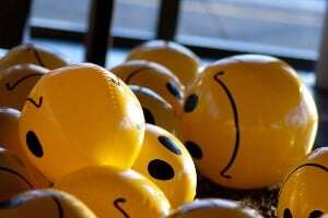 Image shows lots of bouncy balls with smiley faces on them.