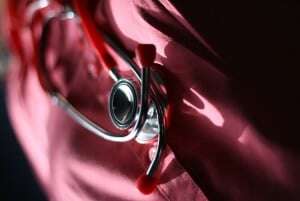 Image shows a stethoscope against pink fabric.