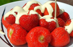 Image shows strawberries with cream poured on top.