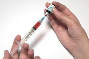 Image shows someone filling a syringe.