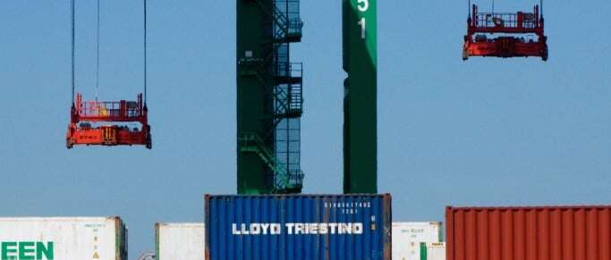 Image shows containers being stacked in a port.