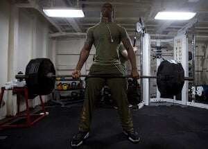 Image shows a man lifting a huge set of dumbbells. 