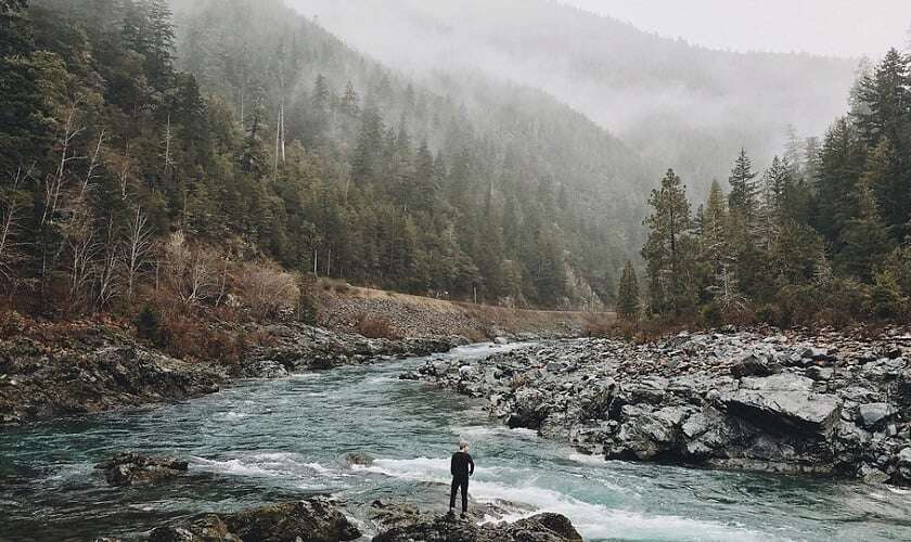 Image shows a man looking out over the wilderness, as if trying to decide which way to go.