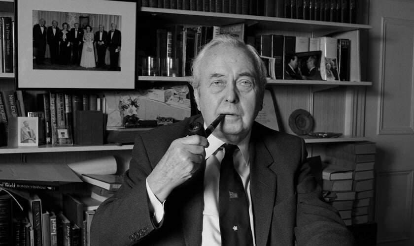 Image shows a black and white photo of Harold Wilson smoking a pipe