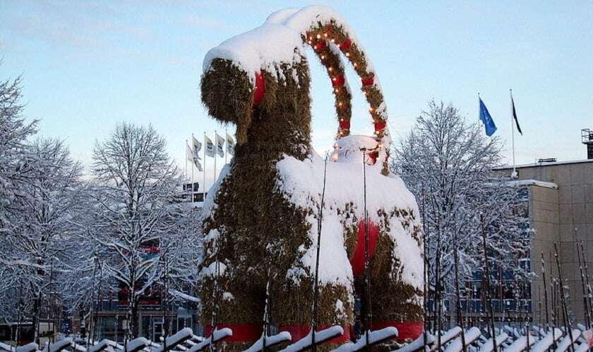 Image shows a huge straw goat, dusted with snow.