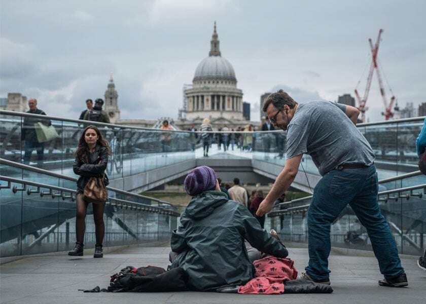 A man gives money to a homeless person.