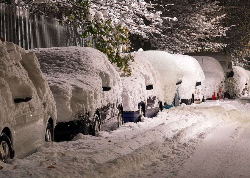 Snowed-in cars by roadside.