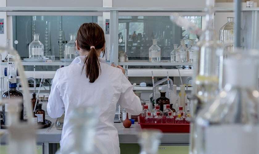 Image shows a woman in a chemistry laboratory.