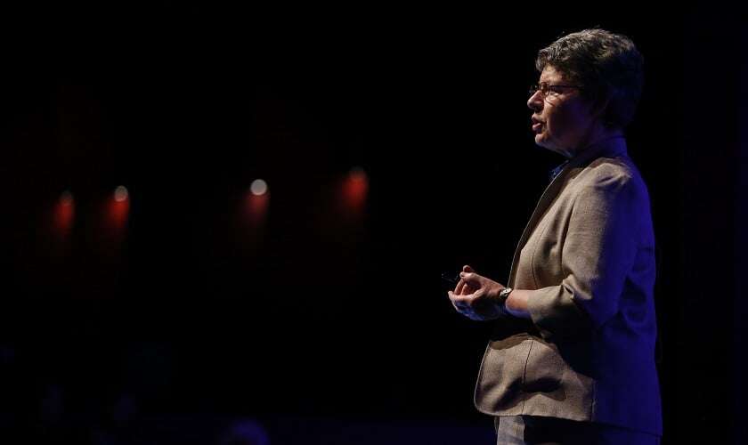 Image shows Bell Burnell speaking on a stage, the audience in shadow.