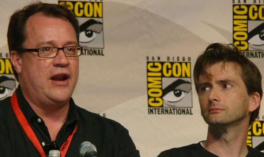 Image shows Russell T Davies and David Tennant on a panel together at Comic-Con. 